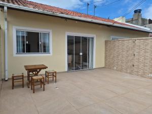 a patio with a wooden table and two stools at Casinha Encantada da MaLu in Itapema