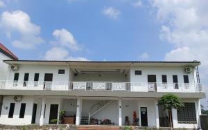a white building with a balcony on top of it at Pendopo Kayuwanan Syariah Near Terminal Giwangan in Yogyakarta