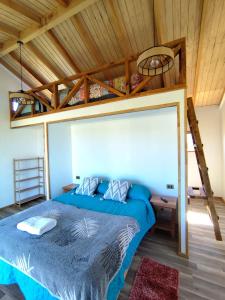 a bedroom with a blue bed with a loft at Hostal y Domos Bello Horizonte in Villarrica