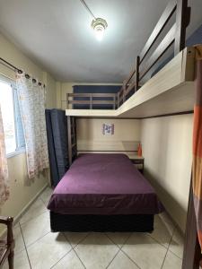 a bedroom with a purple bed and bunk beds at Apto Lilas in Mongaguá