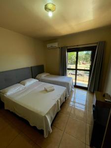 a bedroom with two beds and a large window at Hotel Barichello in São Miguel das Missões