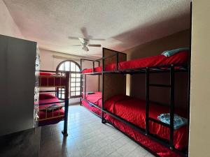 a room with three bunk beds with red sheets at Casona Luciérnaga-Casa de Huéspedes Centro de León, Poliforum in León