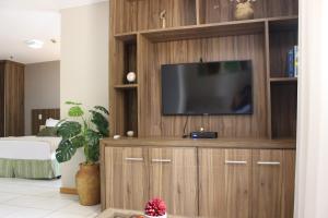 a living room with a television on a wooden entertainment center at ApartHotel - Nobile Suites Monumental Brasília in Brasília