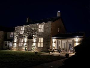 a building with lights on the front of it at night at The Farm House in Skipton