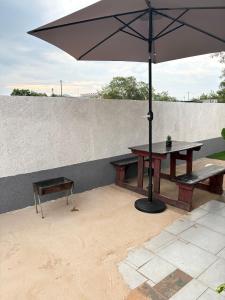 a picnic table with an umbrella and a bench at Hlones place in Rustenburg