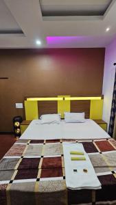 a bedroom with a large bed with a yellow wall at Oudh blooms in Shoranūr