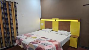 a bedroom with a bed with a yellow headboard at Oudh blooms in Shoranūr