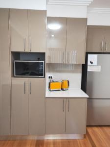 a kitchen with gray cabinets and a yellow appliance at Sea La Vie in Shellharbour