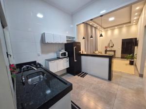 a kitchen with a sink and a refrigerator in it at Casa Alves Próx Hospital do Amor Com Suíte e Ar in Barretos