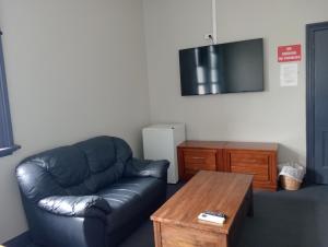 a living room with a leather couch and a coffee table at Australia Hotel Fremantle in Fremantle