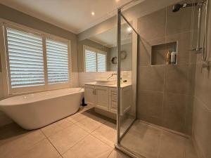 a bathroom with a tub and a sink and a shower at The Grand Oasis in Donvale +8 photos