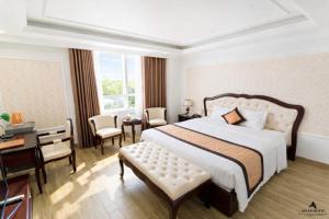 a bedroom with a large bed and a desk and chairs at Asean Hotel in Hải Dương