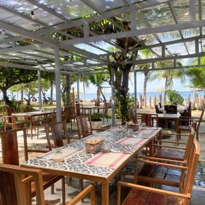 a restaurant with tables and chairs with the beach in the background at Gold View Beachfront Resort in Timbaon