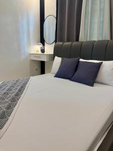 a white bed with blue pillows and a mirror at Skyline Abode Antipolo in Antipolo