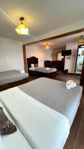 a bedroom with a large white bed and a living room at Hostal Mago in Tlaxcala de Xicohténcatl