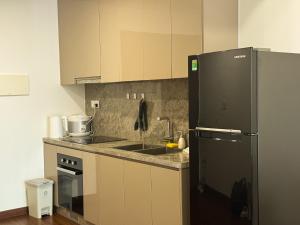 a kitchen with a black refrigerator and a sink at A Quiet Stay - Service Apartment, Vinhome Ocean Park, Ha Noi in Gia Lâm Pho