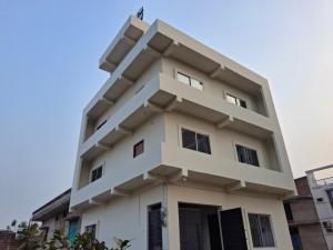 a tall white building with a blue sky in the background at Vamika Palace in Ayodhya