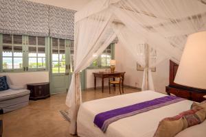 a bedroom with a canopy bed and a table at Samudra Beach Villa in Habaraduwa Central