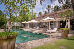 a swimming pool with chairs and umbrellas next to a house at Samudra Beach Villa in Habaraduwa Central