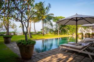 an umbrella and lounge chairs next to a swimming pool at Samudra Beach Villa in Habaraduwa Central