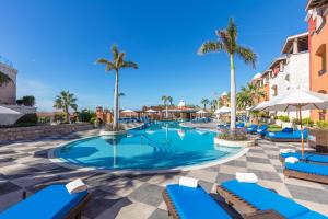 a pool at the resort with blue lounge chairs and palm trees at Hacienda Encantada Resort & Residences in Cabo San Lucas
