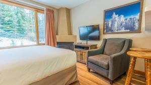 a bedroom with a bed and a chair and a television at Cahilty #247 in Sun Peaks