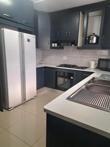 a kitchen with blue cabinets and a white refrigerator at 83 Ocean View in Port Shepstone