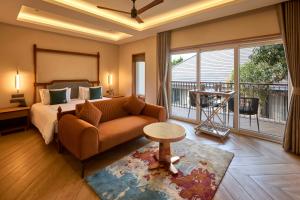 a bedroom with a couch and a bed and a balcony at The Passport Hotel in Assagao