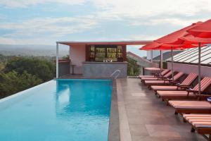 a swimming pool with chairs and umbrellas on a house at The Passport Hotel in Assagao