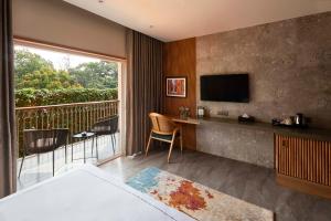 a hotel room with a balcony with a television at The Passport Hotel in Assagao