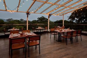 a restaurant with tables and chairs on a deck at The Passport Hotel in Assagao