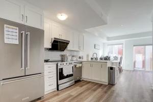 a kitchen with white appliances and a wooden floor at Downsview Park Luxury Townhome near Yorkdale Transit in Toronto