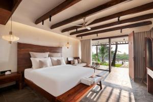 a bedroom with a large white bed and a patio at Riva Beach Resort in Mandrem