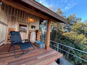 a chair sitting on a deck of a cabin at 椿ハウス 海の見えるサウナ付き貸切別荘 in Anan