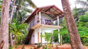 a house with a balcony in the middle of trees at Isuru Homestay Pidurangala in Sigiriya
