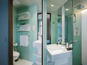 un bagno con due lavandini e una doccia in vetro di Design Hotel Plattenhof a Zurigo