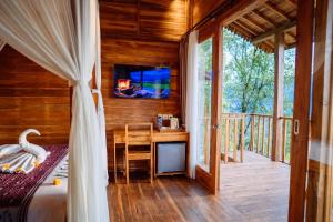 a bedroom with a bed and a desk with a television at Kubu Cemara Sidemen in Karangasem