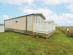 a mobile home with a porch and a fence at Trewan Chalet in Holyhead