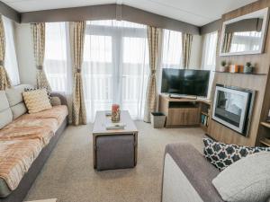 a living room with a couch and a tv at Trewan Chalet in Holyhead