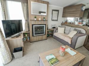 a living room with a couch and a tv at Trewan Chalet in Holyhead
