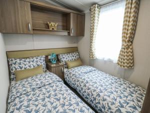 a bedroom with two beds and a window at Trewan Chalet in Holyhead