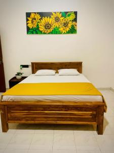 a bedroom with a wooden bed with yellow sheets at Delmar Homestay in Dickwella +1 photo