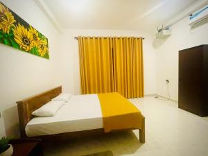 a bedroom with a bed and a yellow curtain at Delmar Homestay in Dickwella