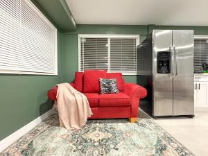 a red chair in a kitchen with a refrigerator at Vancouver UBC 3BD Garden Suite in Vancouver