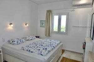 a bed in a white room with a window at Villa Kamari in Kastraki +63 photos