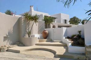 a white house with stairs and a vase at Villa Kamari in Kastraki