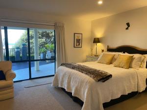 a bedroom with a bed and a sliding glass door at Maison Blue - Chic Garden Apartment - Pet Friendly in Napier