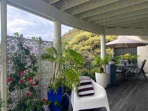 a porch with plants and a white bench and an umbrella at Maison Blue - Chic Garden Apartment - Pet Friendly in Napier