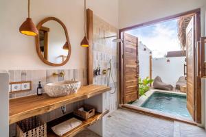 a bathroom with a tub and a sink and a mirror at Teman Private villa with pool in Gili Islands