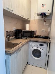 a kitchen with a washing machine and a microwave at Apartment Saturn in Galaţi
